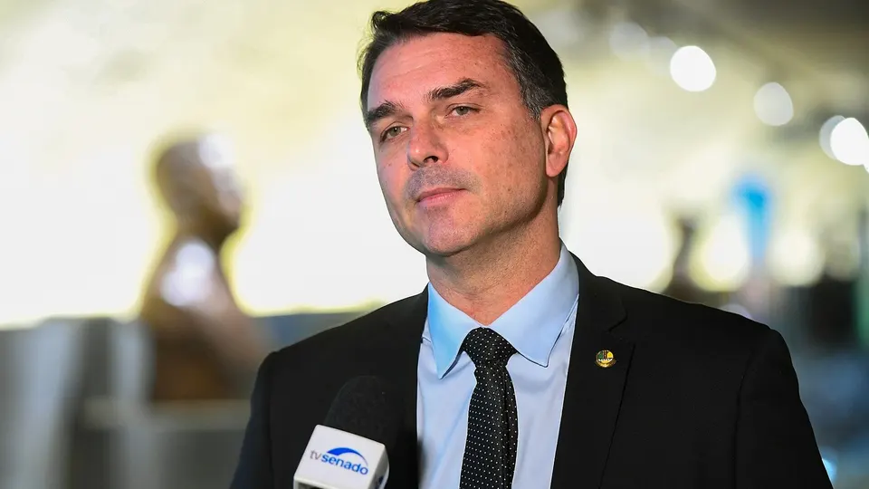 Flávio Bolsonaro de terno, falando em entrevista no Senado