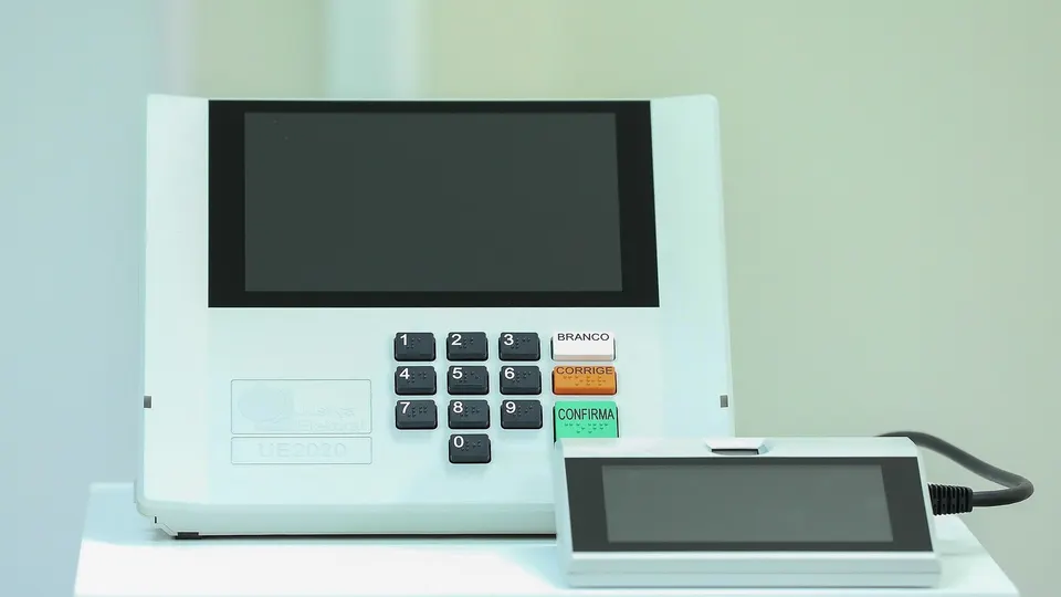 Urna eletrônica brasileira modelo UE2020 sobre mesa, com teclado e tela