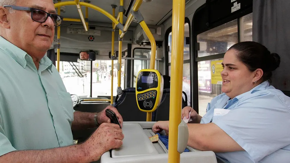 Passageiros embarcando em ônibus urbano em terminal de transporte público